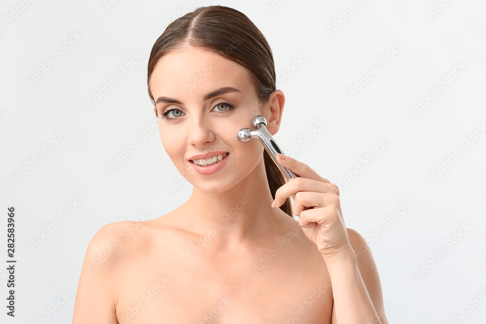 Beautiful woman with facial massage tool on white background Beautiful woman with facial massage tool on white background