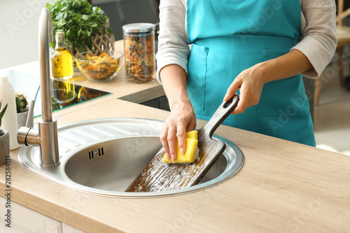 Bild auf Leinwand Woman washing wooden board in kitchen sink