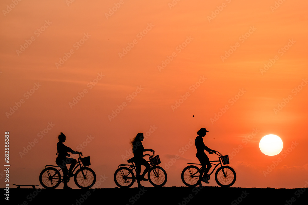 Silhouette of people riding a bicycle in a amazing sunset in Cartagena, Colombia