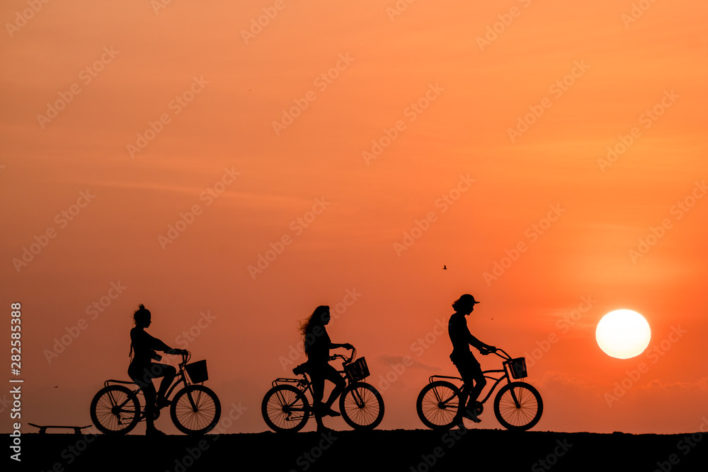 Silhouette of people riding a bicycle in a amazing sunset in Cartagena, Colombia Silhouette of people riding a bicycle in a amazing sunset in Cartagena, Colombia