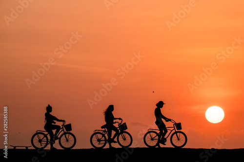 Silhouette of people riding a bicycle in a amazing sunset in Cartagena, Colombia