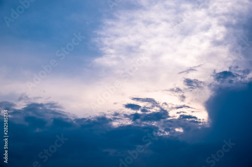 The sun started to shine with orange rays of light in the cloudy sky after the big thunderstorm.
