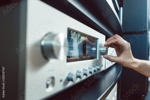 Hand of woman turning up volume of Hi-Fi amplifier photo