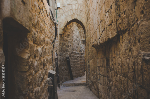 old city Jerusalem back street narrow alley with with arch passage between high stone and brick walls 