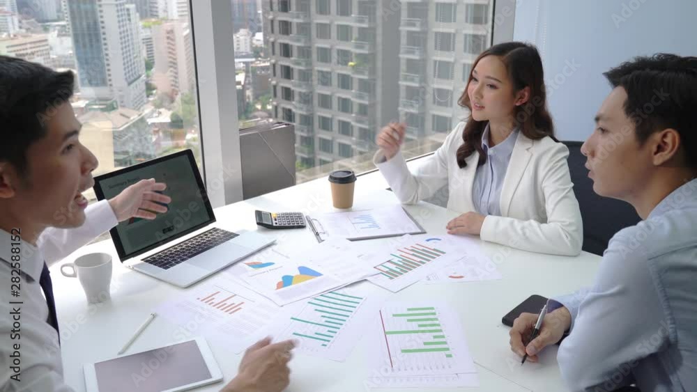Asian business team discussing financial plan charts and graphs at meeting room in modern city office Asian business team discussing financial plan charts and graphs at meeting room in modern city office