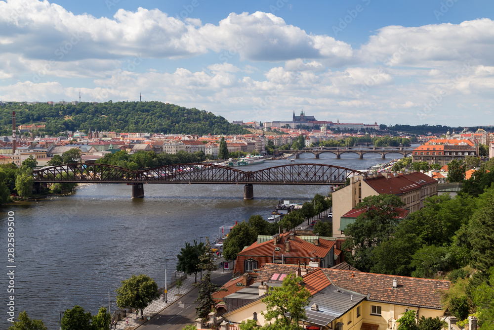 View of the city and bridges over the Vltava River in Prague, Czech Republic, on a sunny day in the summer. Prague (Hradcany) Castle is the background.