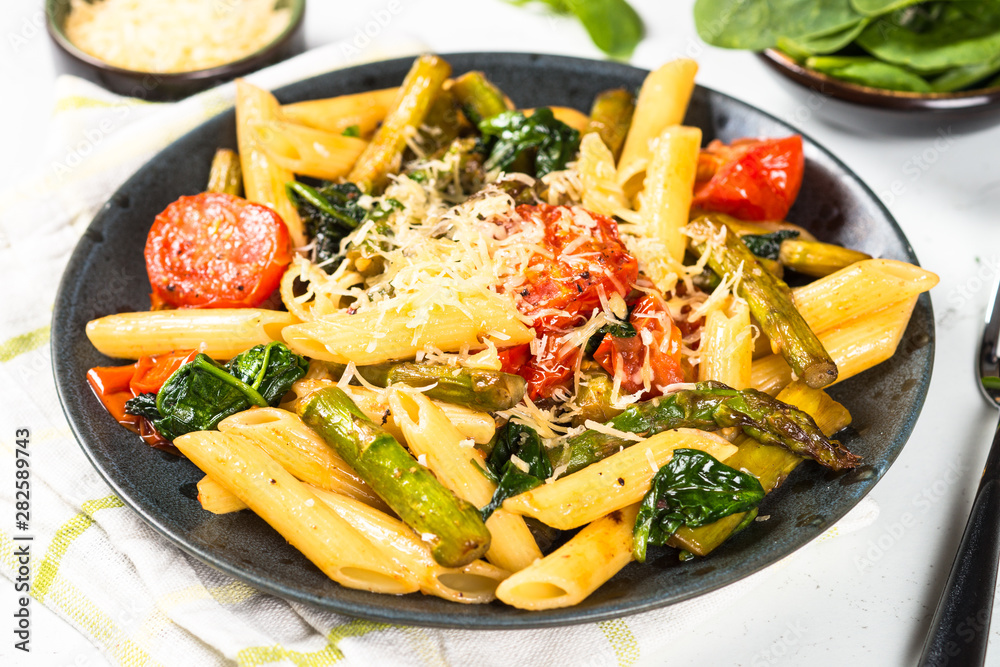 Vegan pasta penne with spinach, asparagus and tomato.