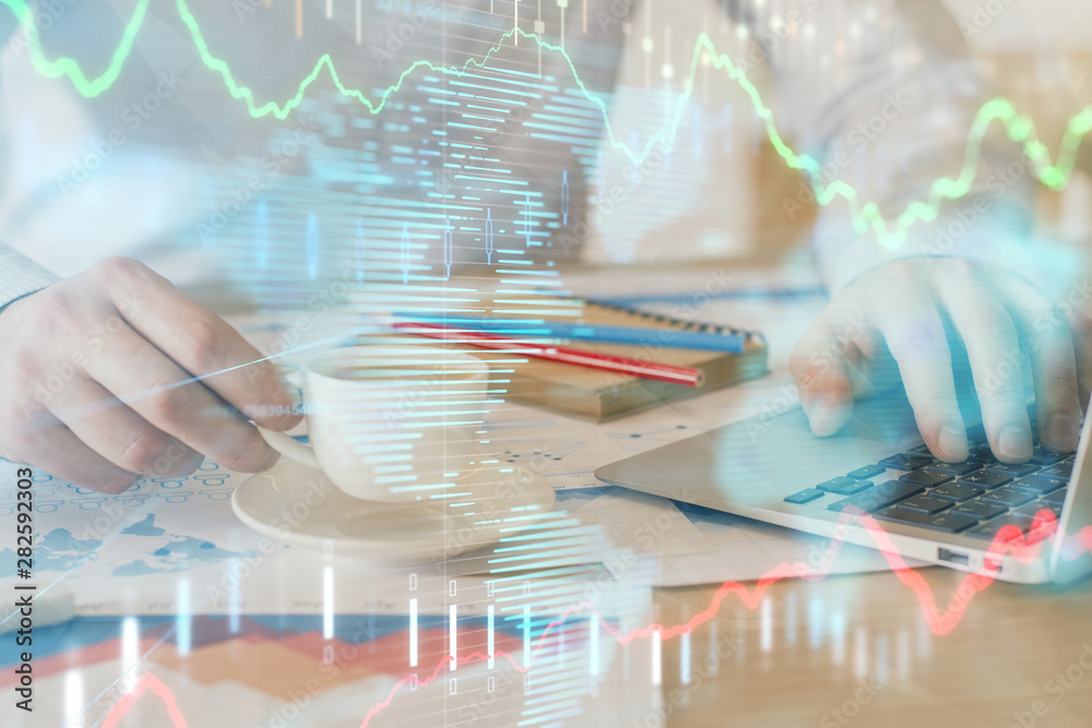 Forex graph with businessman working on computer in office on background. Concept of hardworking. Double exposure.