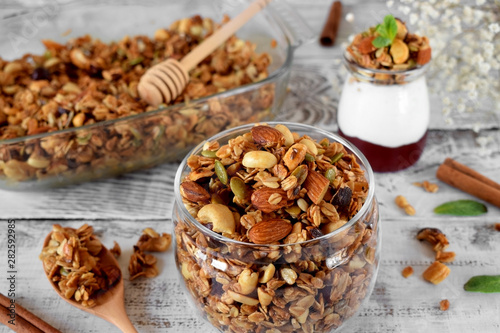 Granola with different nuts in a glass jar on the white wooden table