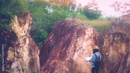 Back of solo travel in local asia, Teenager traveler holding map while hiking on mountain, Solo tourist traveller with map standing on top of stone hill background, Summer travel vacation