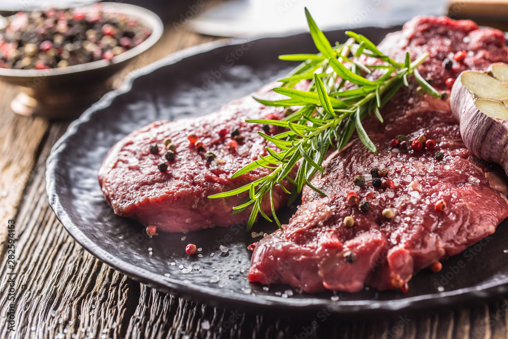 Beef meeat Rib-Eye steak wit rosemary salt and pepper on black plate Beef meeat Rib-Eye steak wit rosemary salt and pepper on black plate
