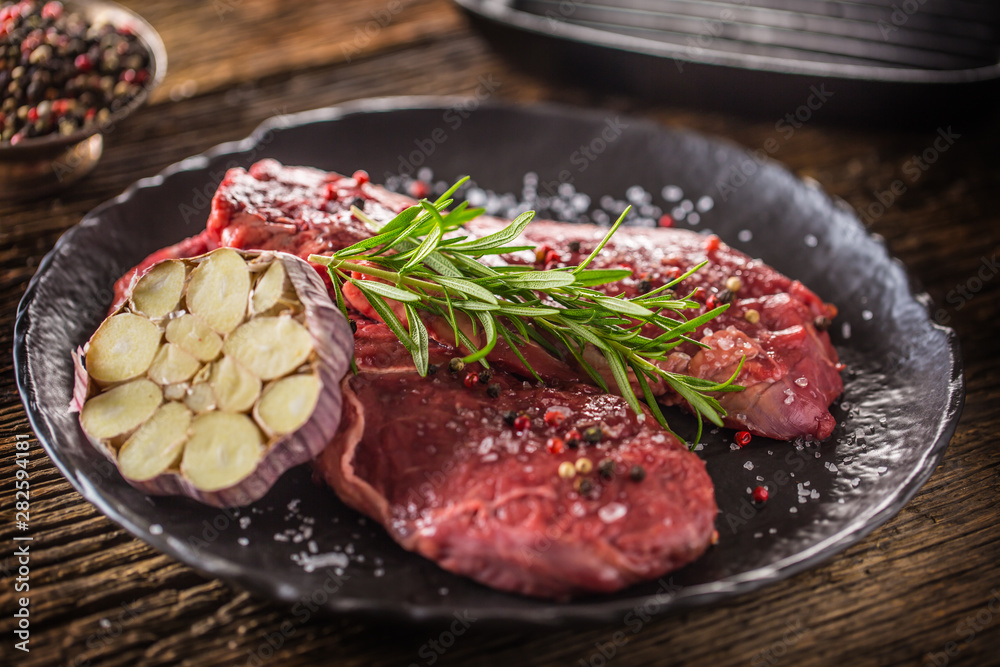Beef meeat Rib-Eye steak wit rosemary salt and pepper on black plate Beef meeat Rib-Eye steak wit rosemary salt and pepper on black plate