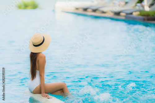 Portrait young asian woman happy smile relax around swimming pool in hotel resort