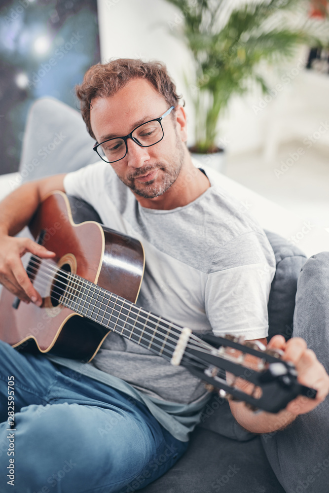 Obraz premium Man playing acoustic guitar in the living room.