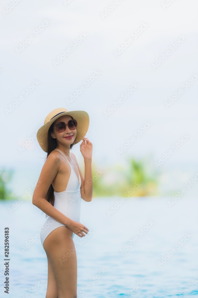 Portrait young asian woman happy smile relax around swimming pool in hotel resort