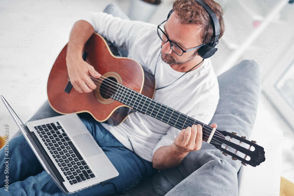 Obraz premium Man playing acoustic guitar in the living room.