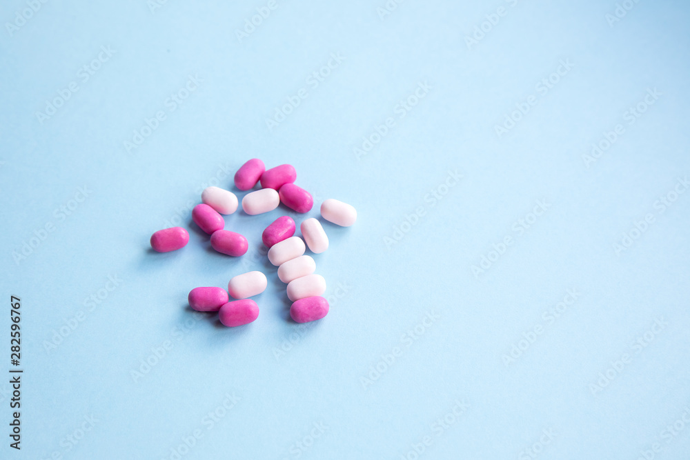 Beautiful pink and white pills on blue background.