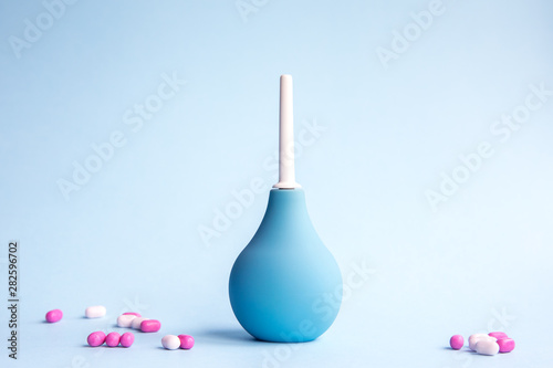 Blue douche and beautiful tablets of pink and white color on a blue background. Medical concept. photo