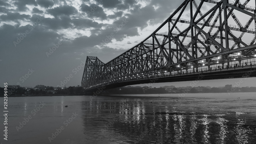 Fototapeta premium Silhouette of Howrah Bridge at the time of Sunrise. Howrah Bridge is a bridge with a suspended span over the Hooghly River in West Bengal.