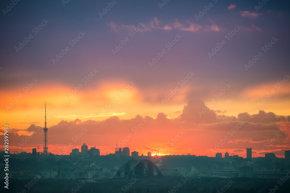 Sunset in the city with silhouette of buildings and sun on orange sky. Kiev, Ukraine