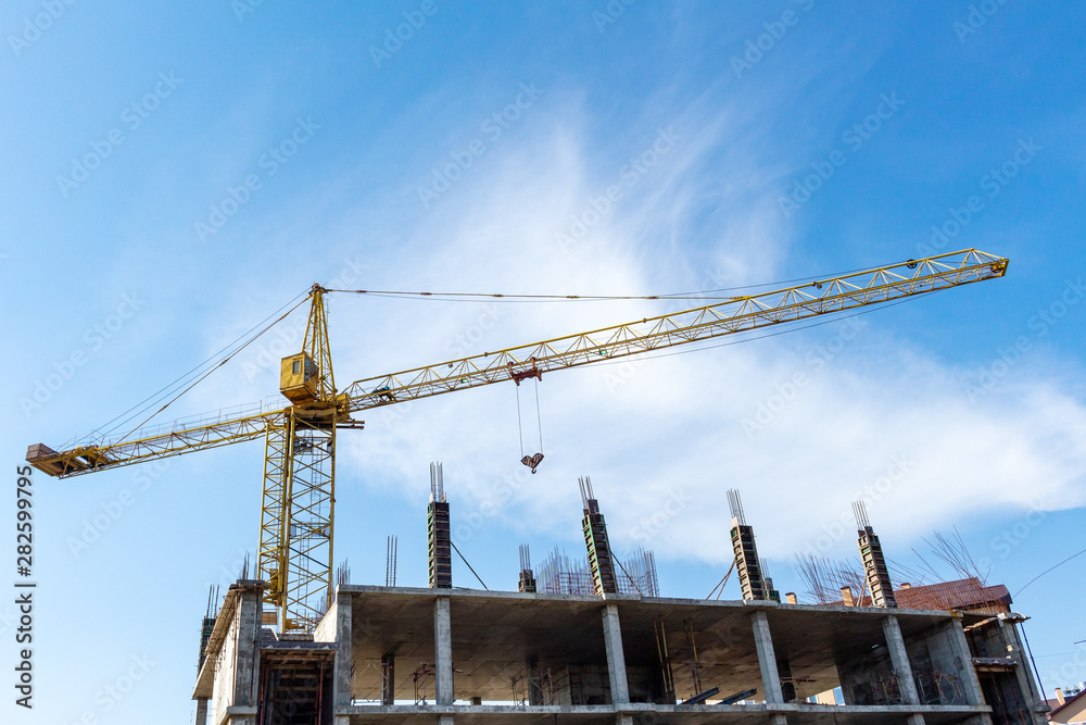 Tower crane on the blue sky background. Building construction work concept, investments in the development construction buildings and structures industry.