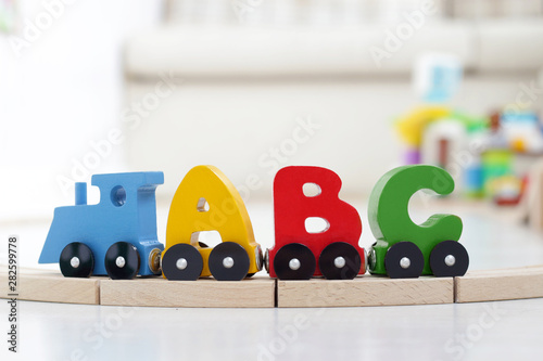 letters of alphabet train on rails in children's playroom. steam train, colorful wagons; wooden toy made of natural eco-friendly material. early childhood development, learning to read, pre-school