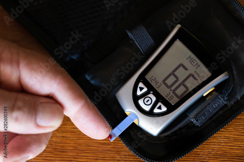 Diabetic man testing his blood sugar levels on glucometer