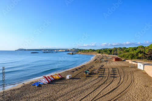 View towards L'Escala from  Sant Marti an empty beach with pedalos, canoes parasols, Catalonia Costa Brava Spain