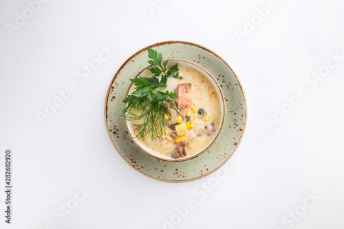 Chowder with salmon, potatoes and corn in ceramic bowl isolated on white background photo