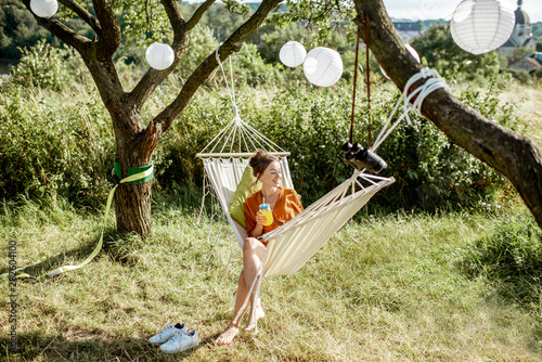 Woman sitting on the hammock, relaxing an the beautifully decorated garden or backyard