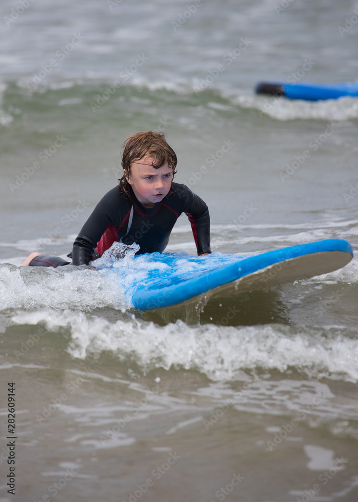 Little boy learning to surf at the beach, getting up on surfboard for the first time, west coast of Ireland Little boy learning to surf at the beach, getting up on surfboard for the first time, west coast of Ireland