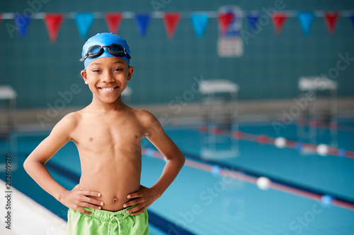 Portrait Of Boy Standing By Edge Of Swimming Pool Ready For Lesson