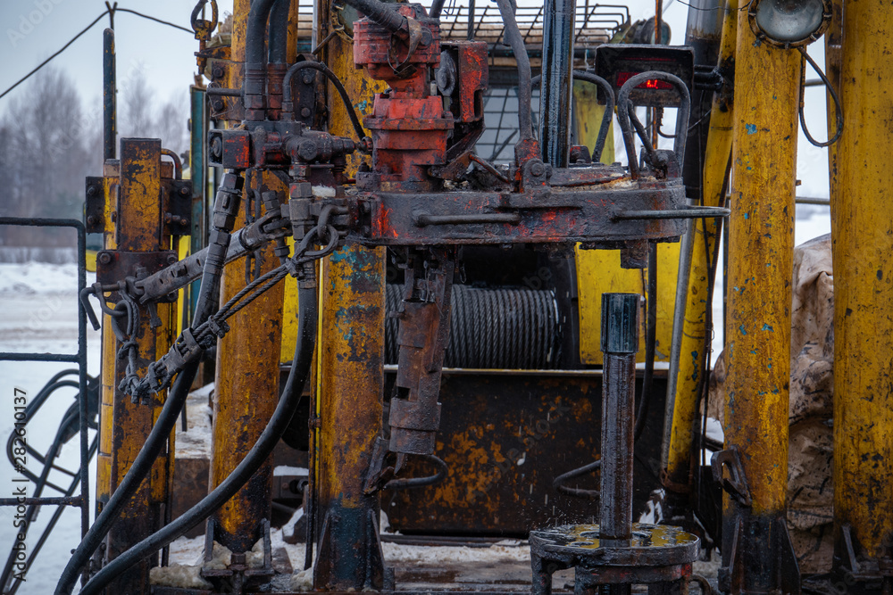 Workover rig working on a previously drilled well trying to restore production through repair. Toned.