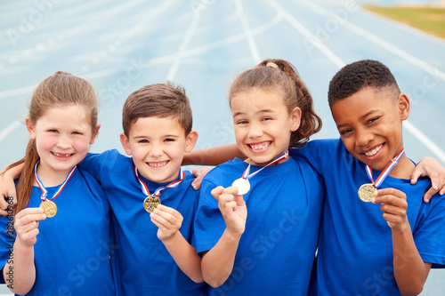 Fototapeta Naklejka Na Ścianę i Meble -  Portrait Of Children Showing Off Winners Medals On Sports Day