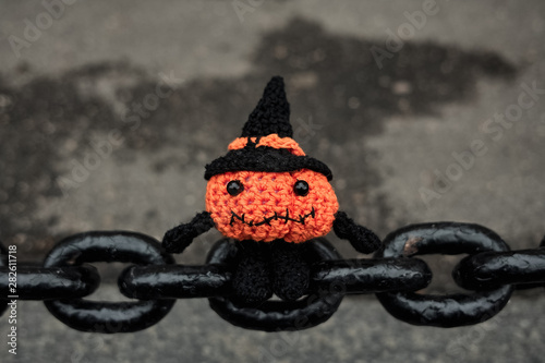 Halloween pumpkin man sits on the links of a large old chain