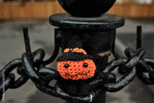 Halloween pumpkin man sits on the links of a large chain