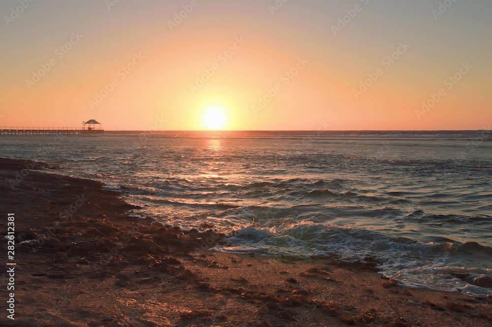 colorful sunrise over a stretch of sea coast