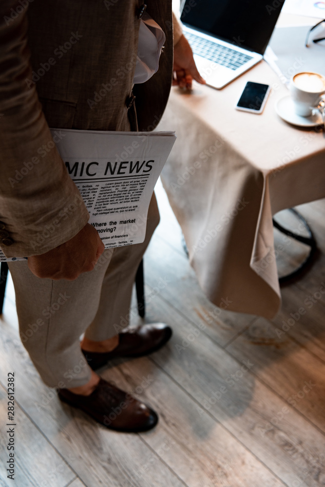 cropped view of businessman holding newspaper in cafe cropped view of businessman holding newspaper in cafe