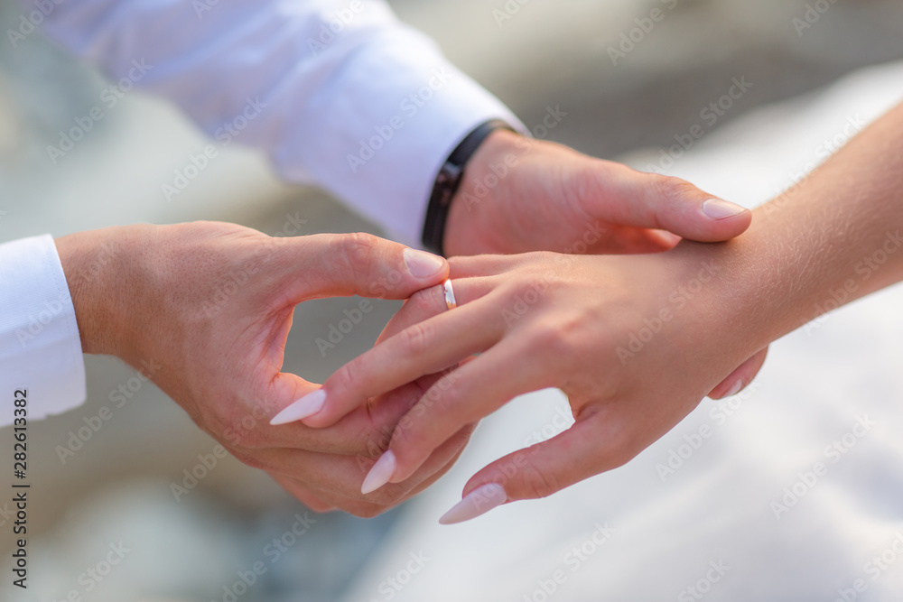 Groom slipping ring on finger of bride at wedding Groom slipping ring on finger of bride at wedding