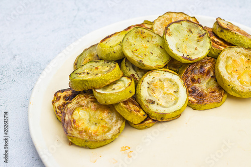 Baked roasted zucchini slices on plate. White background.