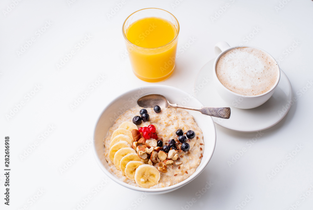 Breakfast with oatmeal with berries and nuts, coffee and orange juice