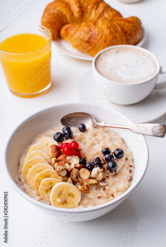 Breakfast with oatmeal with berries and nuts, coffee and orange juice
