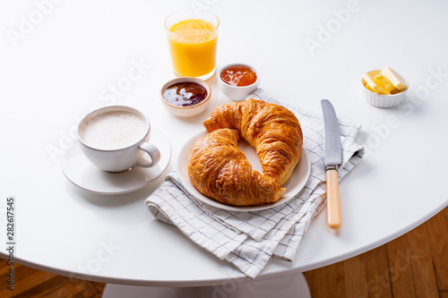 Top view flatlay with fresh croissants served with jams, coffee, orange juice and buter. Morning meal concept. White background photo