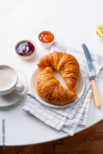 Top view flatlay with fresh croissants served with jams, coffee and buter. Morning meal concept. White background