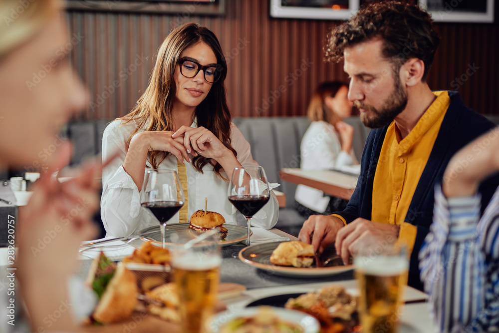 Multiethnic friends sitting at restaurant, drinking alcohol, chatting and having burgers for dinner. Multiethnic friends sitting at restaurant, drinking alcohol, chatting and having burgers for dinner.