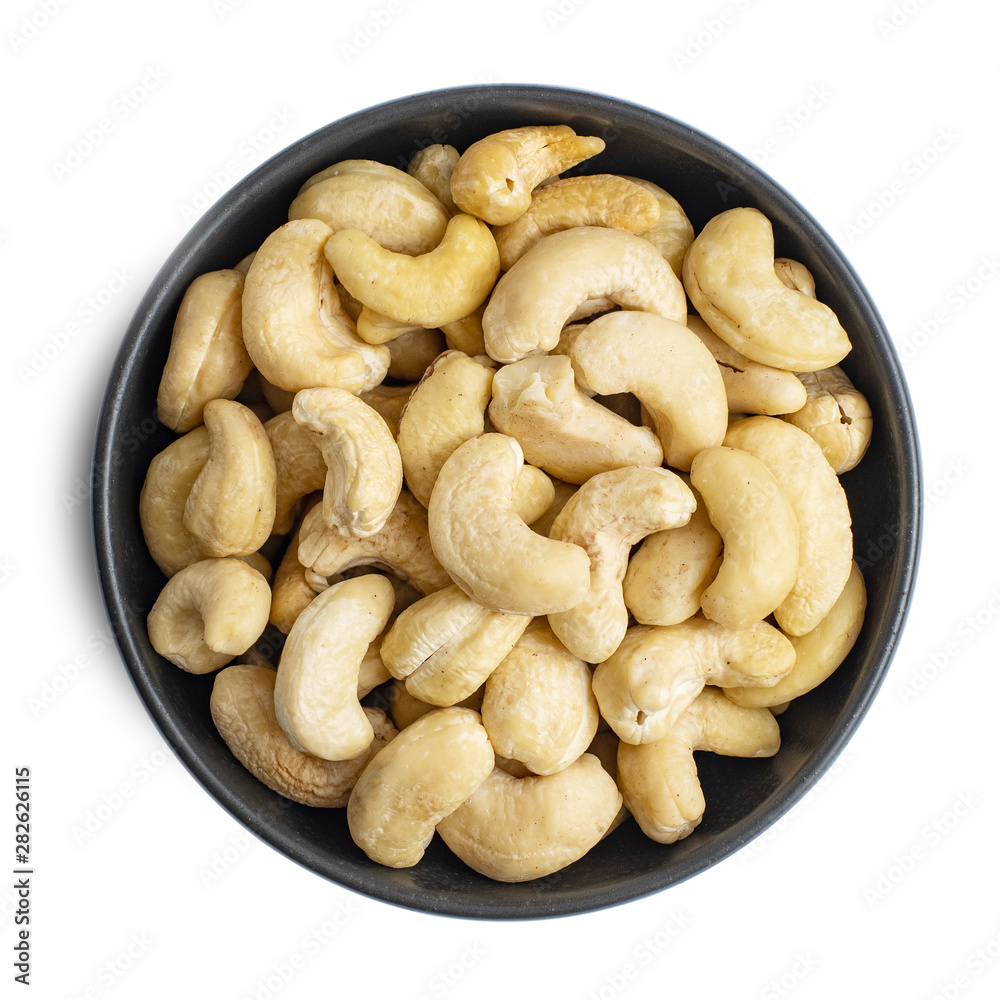 Whole cashews in dark bowl isolated on white background. Top view