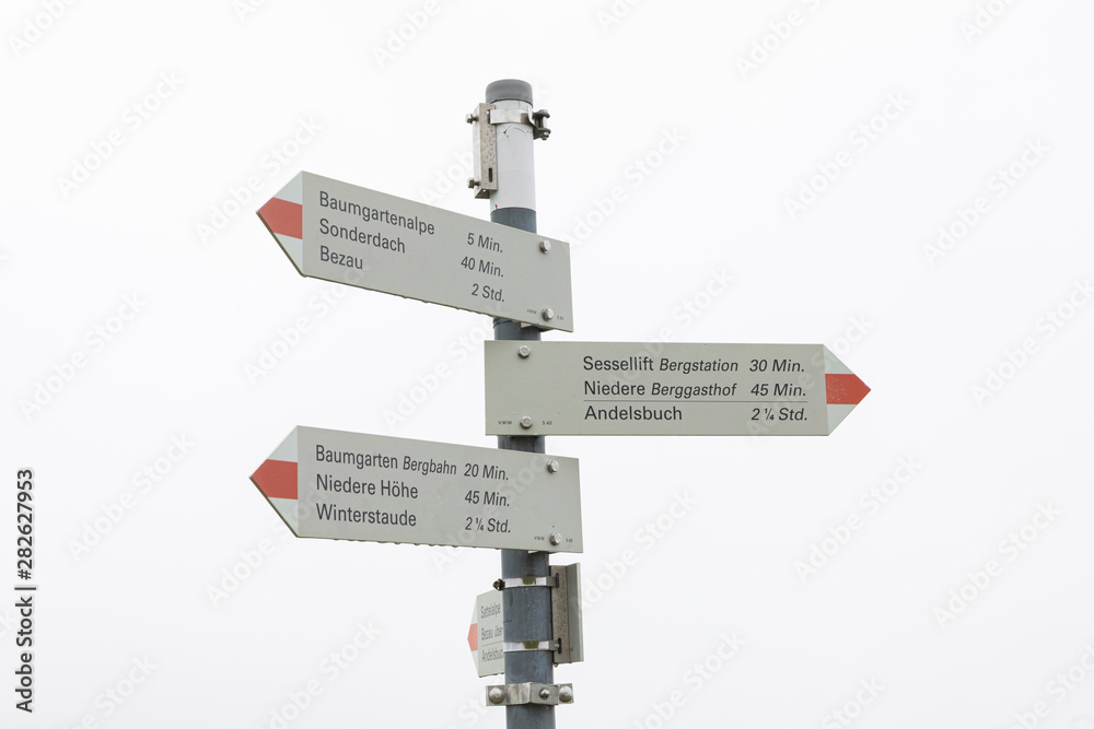 Obraz premium direction sign in the mountains with a whitee misty sky.