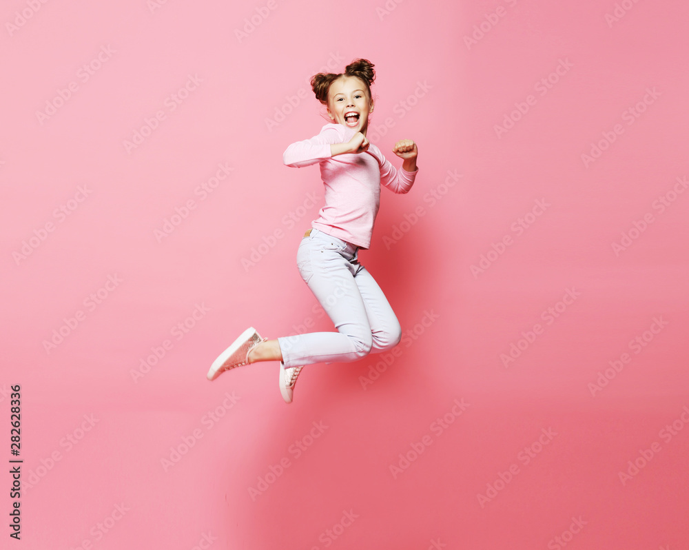  funny child girl dressed casual jumping on pink  background 