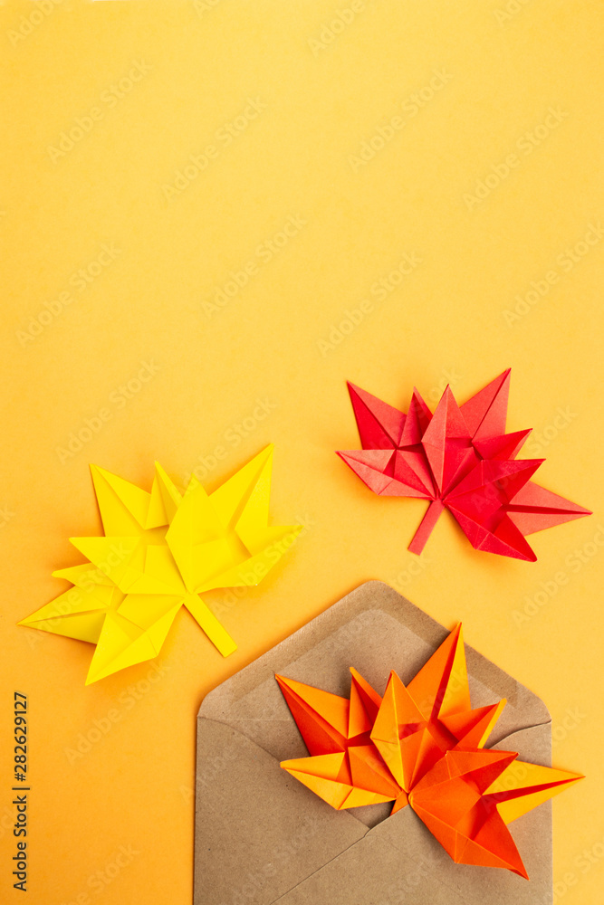 Autumn leaves in an envelope on an orange background. Origami from colored paper. The concept of gifts, discounts, sales, incoming messages. Autumn bright background Autumn leaves in an envelope on an orange background. Origami from colored paper. The concept of gifts, discounts, sales, incoming messages. Autumn bright background