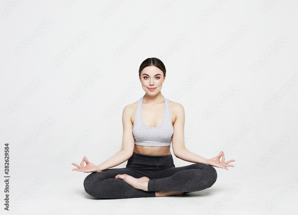 Portrait of attractive woman doing yoga, pilates over light grey background. Healthy lifestyle and sports concept.